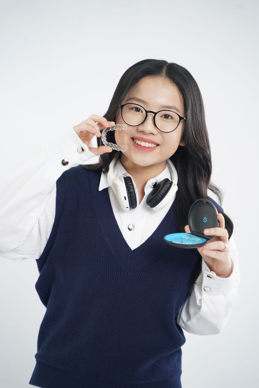 Smiling patient holding her clear Invisalign aligners
